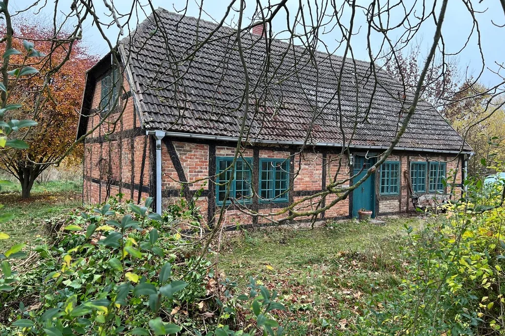 Die Alte Schmiede von Rothspalk: Fachwerkhaus mit Backsteinausfachung, grünen Sprossenfenstern und Ziegeldach im Herbst