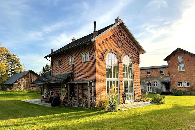 Die Orangerie von Gut Rothspalk: Backsteinbau mit hohen Rundbogenfenstern im Abendlicht